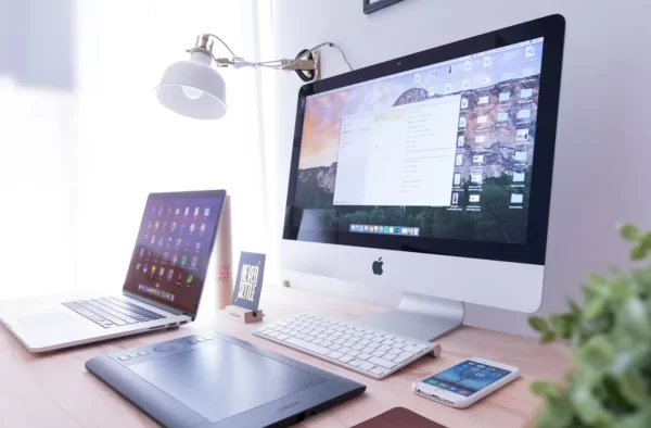 iMac, laptop and phone on workstation table